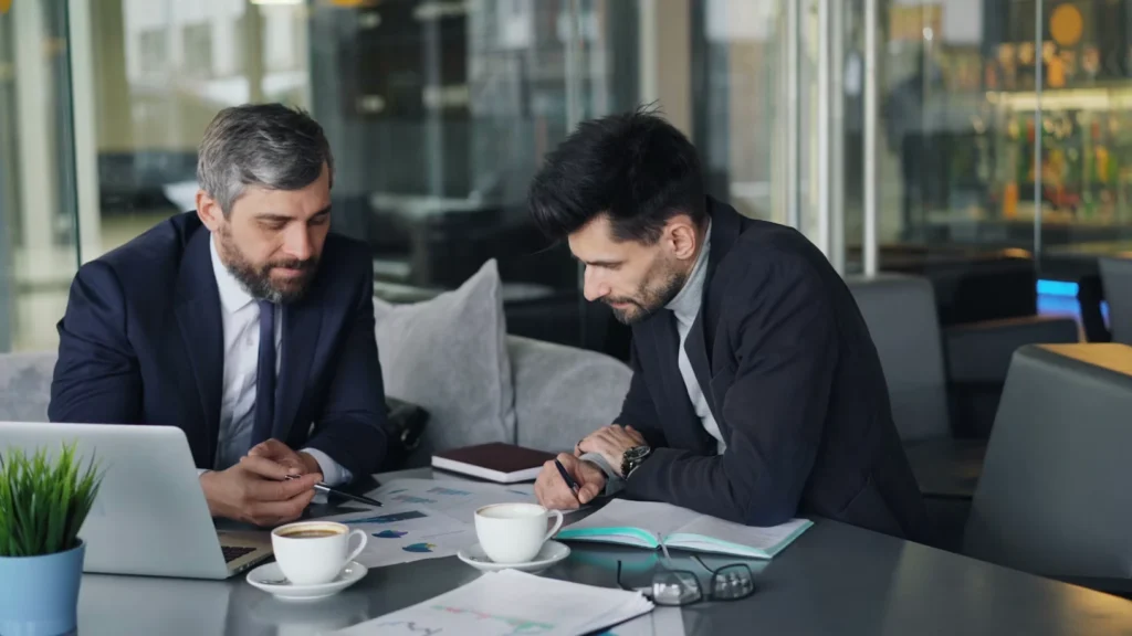 Two business consultants discussing work over laptops