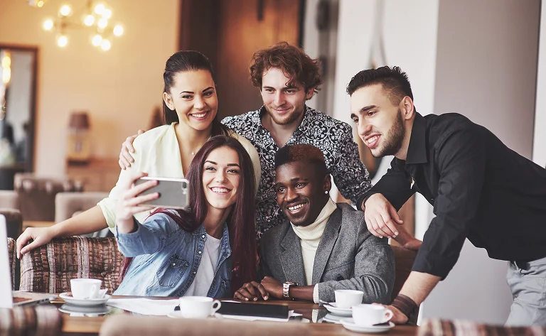 five smiling friends take a selfie together indoor