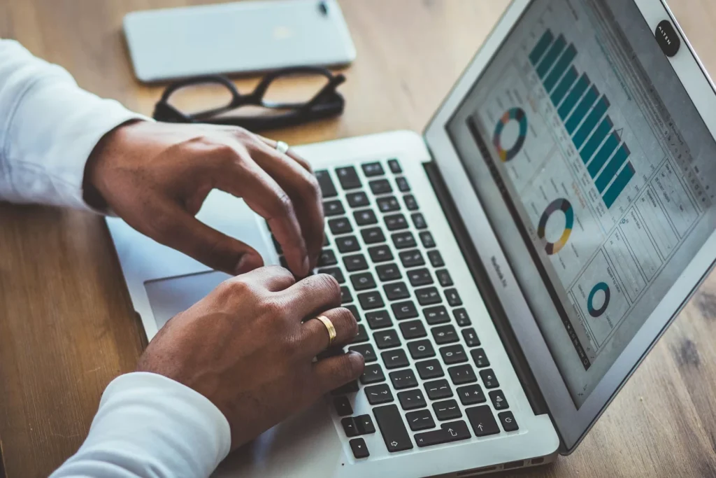 Hands typing on a laptop showing an analytics dashboard