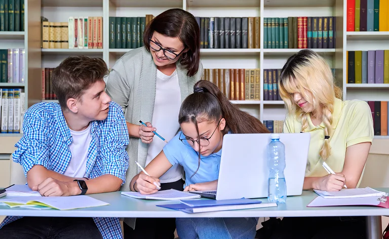students studying together with teacher in library