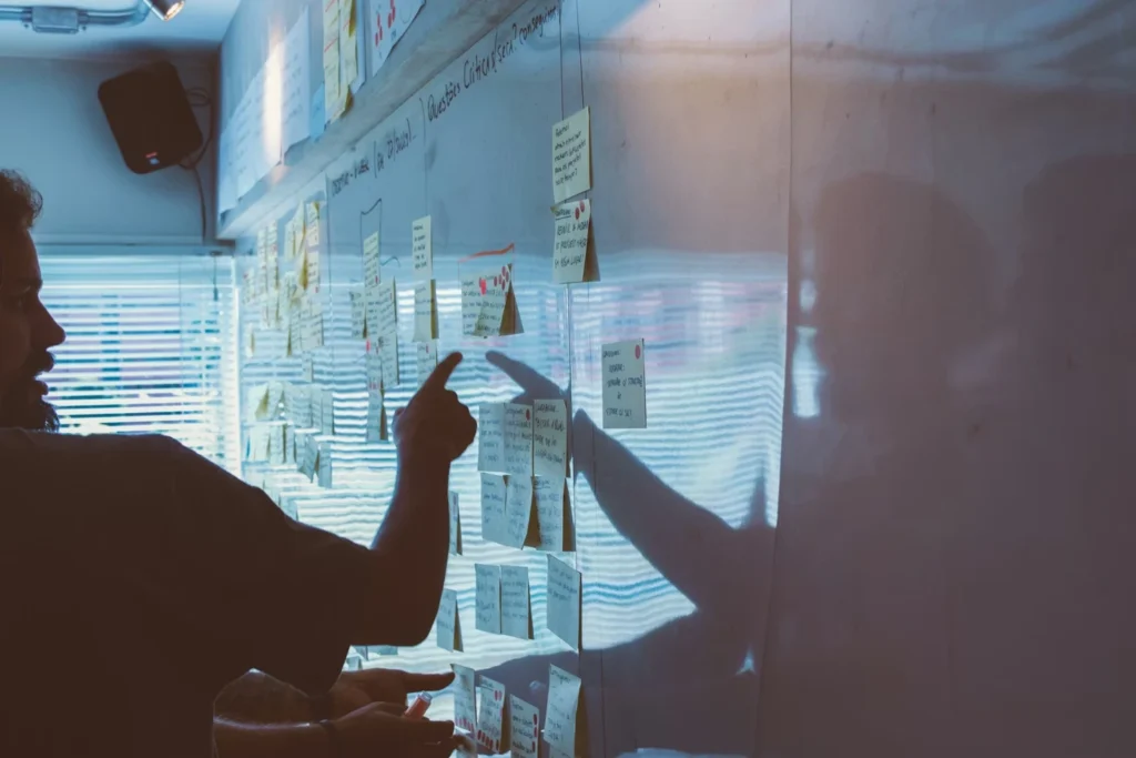 Team member pointing at sticky notes on a planning wall