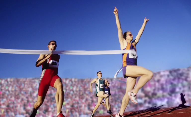 athletes running towards finish line on a sunny day