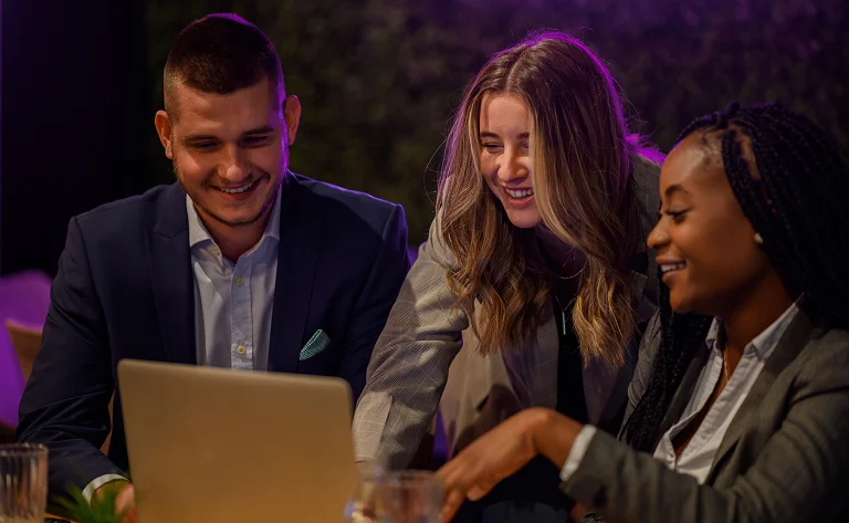 smiling colleagues collaborate on laptop in urban